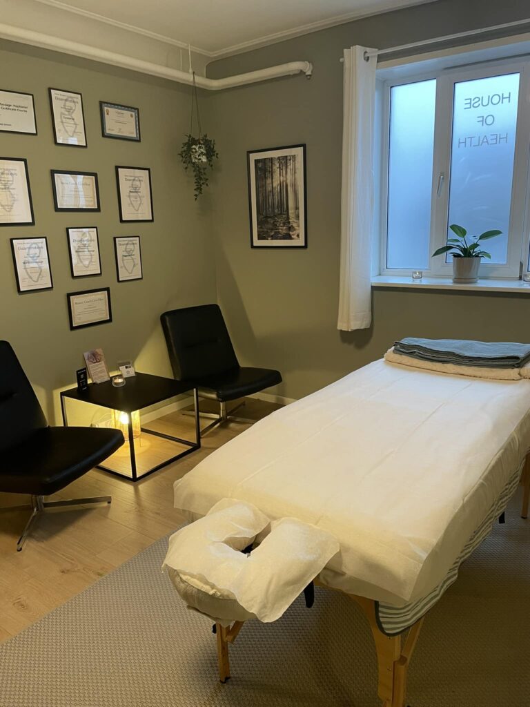 Roligt massagesalon rum med behandlingsbriks og diplomer